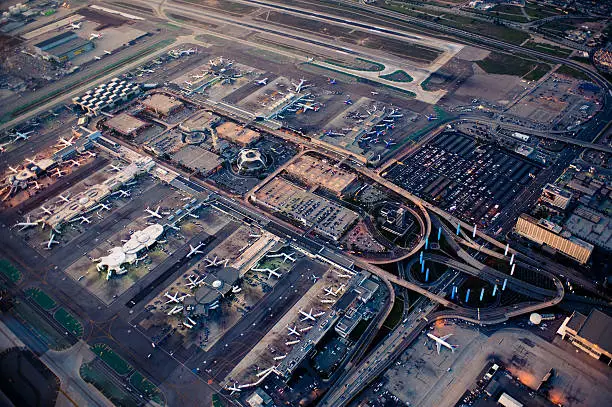 Los Angeles International Airport (LAX) stays busy under a setting sun as nighttime lights start to turn on.