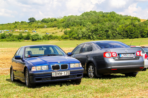Budapest, Hungary - July 26, 2014: Motor cars BMW E36 3-series and Volkswagen Jetta are parked at the grass field.