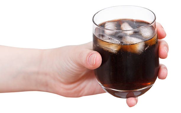 istock hand holds cola with ice in glass isolated 500340081