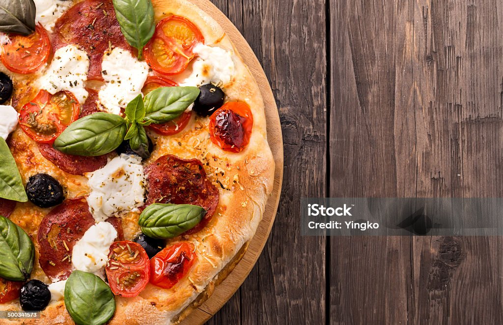 Rústico pizza com salame, queijo muçarela, azeitonas e manjericão em madeira - Foto de stock de Pizza royalty-free