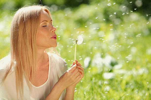 istock girl blowing on a dandelion 500342773