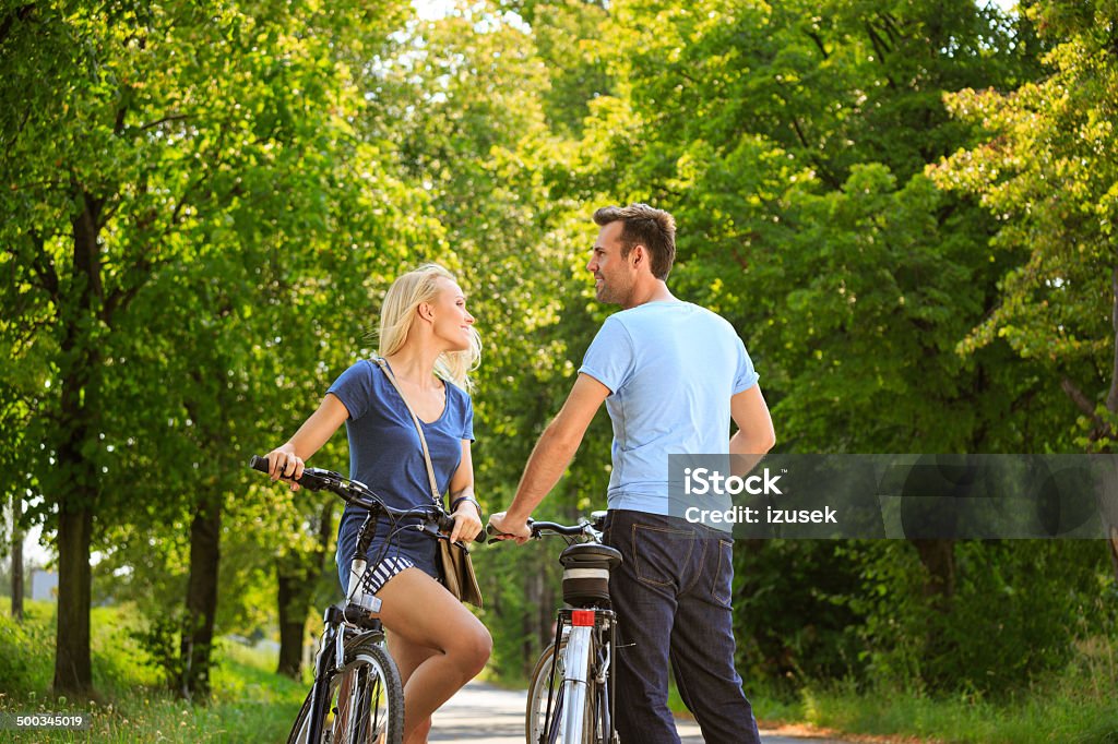 Happy couple in a park Outdoor portrait of happy couple standing with a bicycles in a park. Bicycle Stock Photo