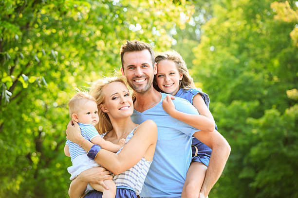 Outdoor portrait of happy parents with their two children. 