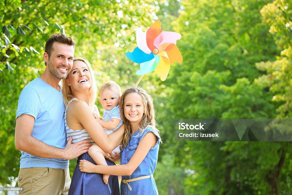 Happy family in the park Outdoor portrait of happy parents with their children. Girl holding a pinwheel. 6-11 Months Stock Photo