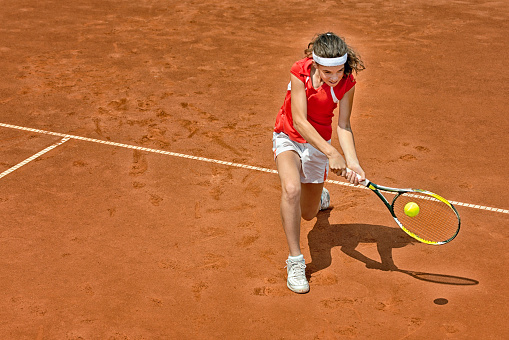 Young woman playing tennis, backhand stroke