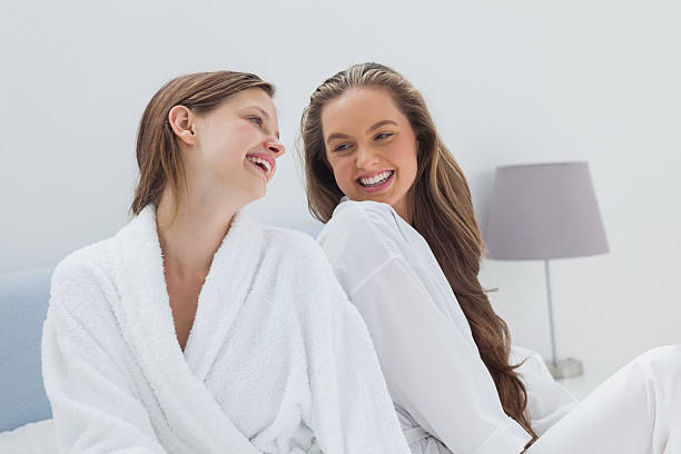 istock Happy friends wearing bathrobe sitting on bed 500346149
