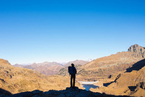 istock Climber on the top looks at a mountain range 500355340