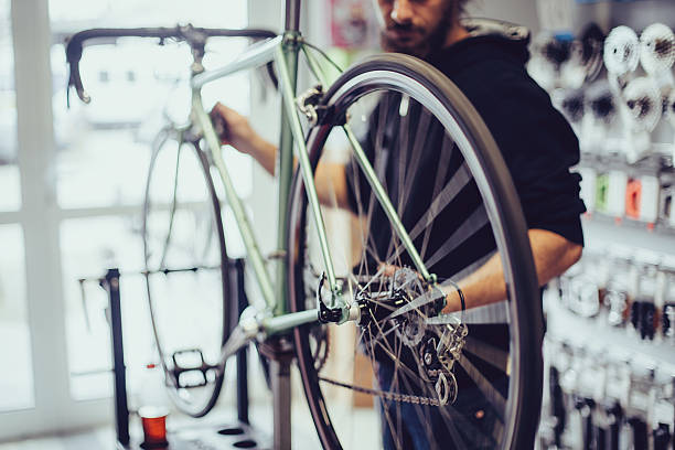 Mechanic repairing a bike Young man working at the bicycle workshop bike workshop stock pictures, royalty-free photos & images
