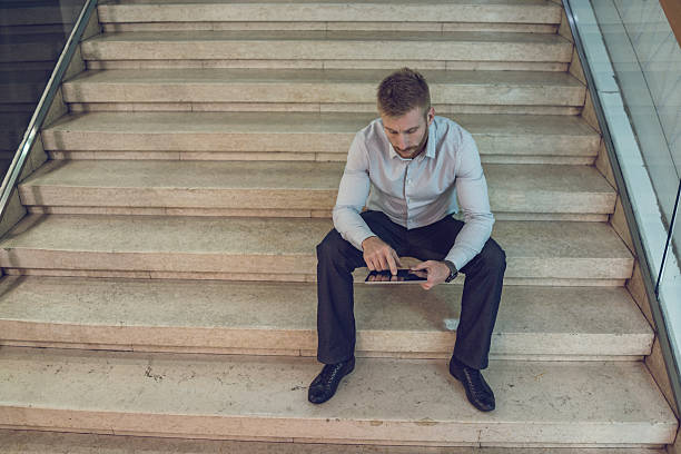 istock Young businessman sitting on staircase and working on touchpad. 500362070