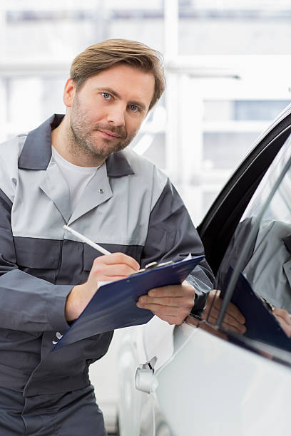 istock mechanic holding clipboard while leaning on car's window in workshop 500362511