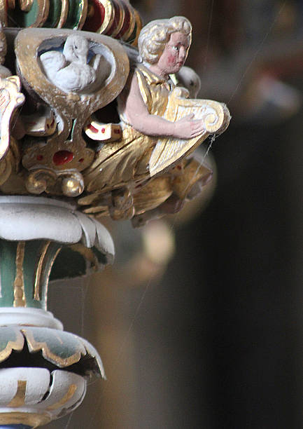 Watching from on-high, a carved angel provides attachment points for an intrepid spider