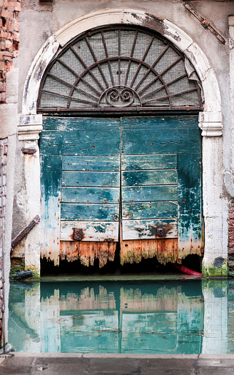 Old door on the water along a water channel in Venice, Italy.