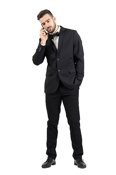istock Sad young man in suit on the phone looking down. 500367960