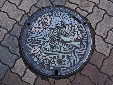 Osaka, Japan - November 20, 2015: A manhole cover in Osaka, Japan. The Osaka castle engraved on to a manhole cover as a symbol of an important city's landmark.
