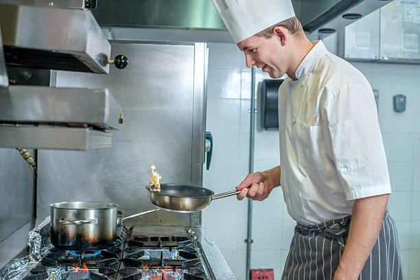 istock Confident chef fries vegetables on frying pan. Young chef 500369694