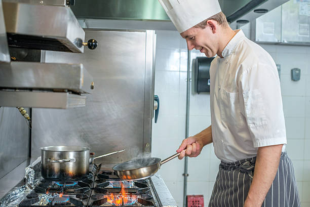 istock Cheerful Chef frying vegetables in  pan. Young chef preparing 500369790