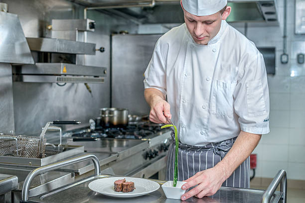 istock Confident Chef decorate plate with meat greens. Young chef prepa 500370270