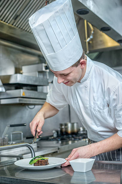 istock Confident Chef decorate plate with meat greens. Young chef prepa 500370320