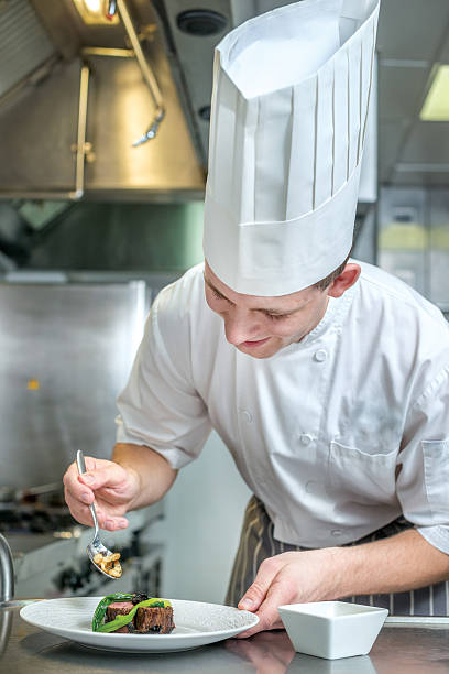 istock Cheerful Chef decorate plate with meat greens. Young chef prepar 500370402
