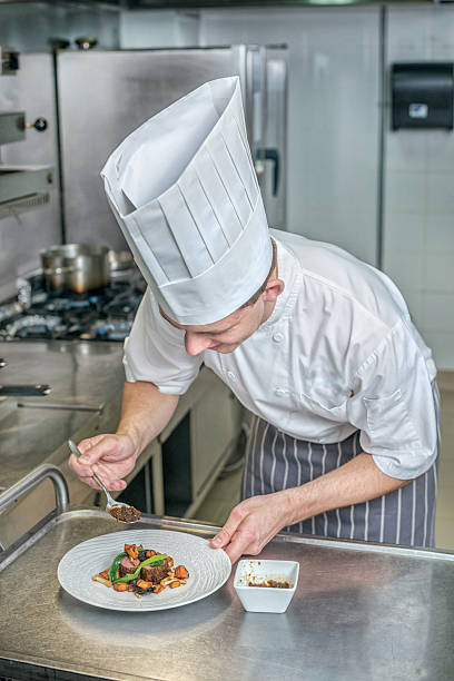 istock Confident chef adds gravy for grilled meat. Young chef preparing 500370498