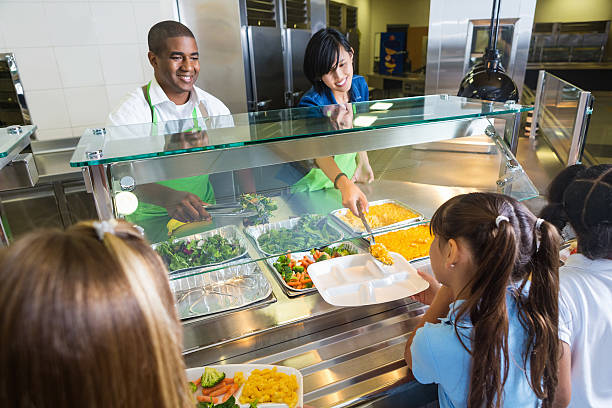 School cafeteria workers offering healthy food options to students School cafeteria workers offering healthy food options to students cafeteria worker photos stock pictures, royalty-free photos & images
