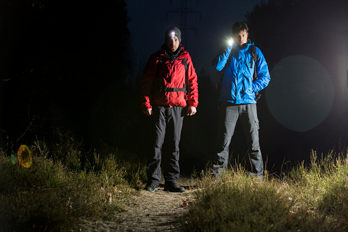 Full length portrait of male hikers with flashlights in field at night