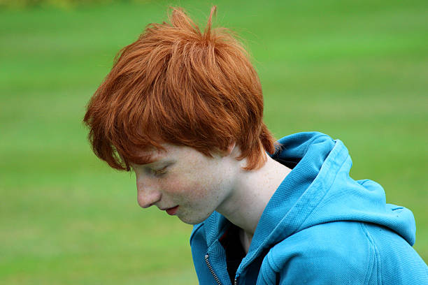istock Young boy, short red hair smiling in garden, looking down 500378869