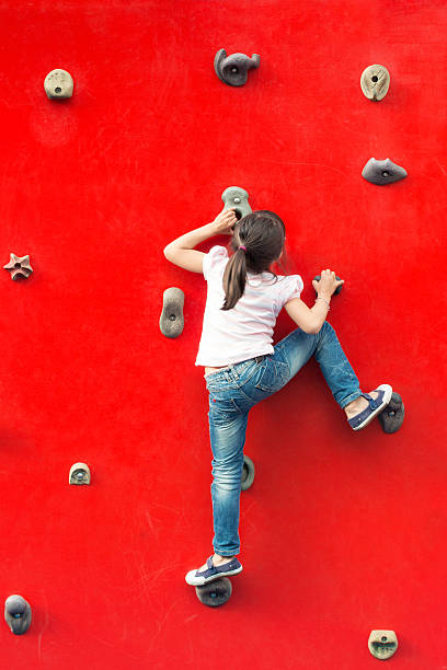Girl climbing a red wall in a playground