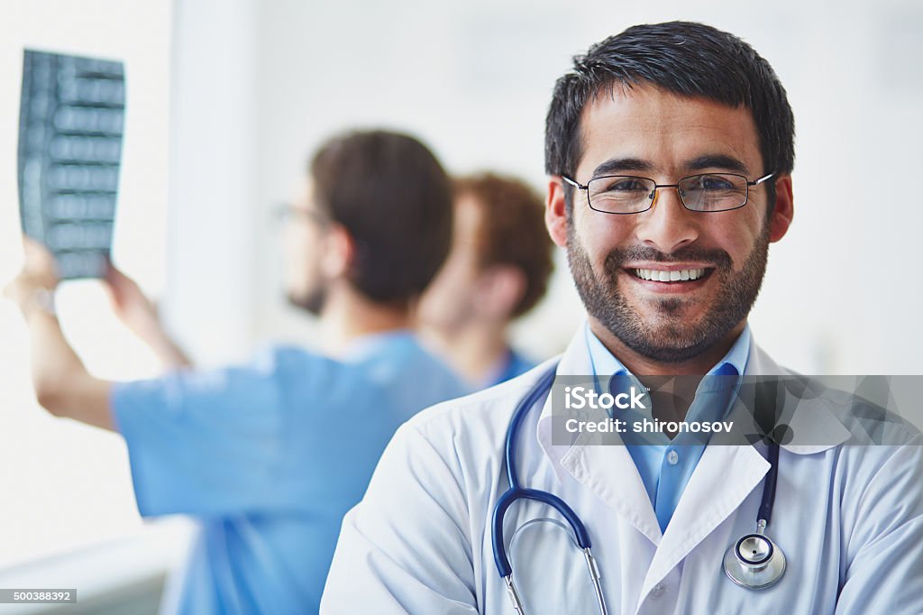 Happy specialist Portrait of smiling doctor looking at camera on background of his working colleagues Adult Stock Photo