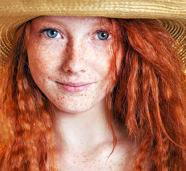 Summer portrait, beautiful freckled young woman wearing straw hat 
