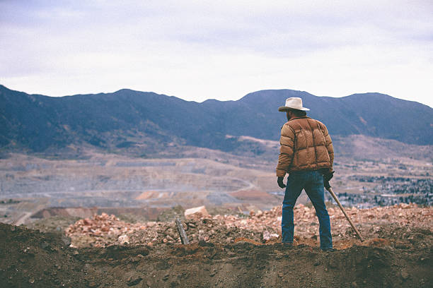 Man walks on mound of work site surrounded by moutains