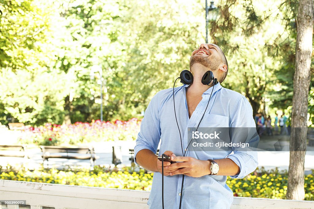 Handsome guy in the light blue shirt posing with headphones handsome guy in the light blue shirt posing with headphones and a phone in his hand Adult Stock Photo