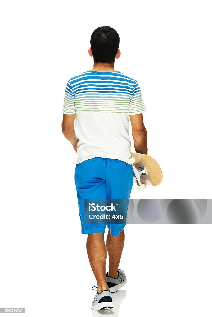 Rear view of man walking & holding skateboard Rear view of man walking & holding skateboardhttp://www.twodozendesign.info/i/1.png 30-39 Years Stock Photo