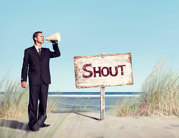 istock Businessman Holding Loudspeaker with Signboard on Beach 500392211