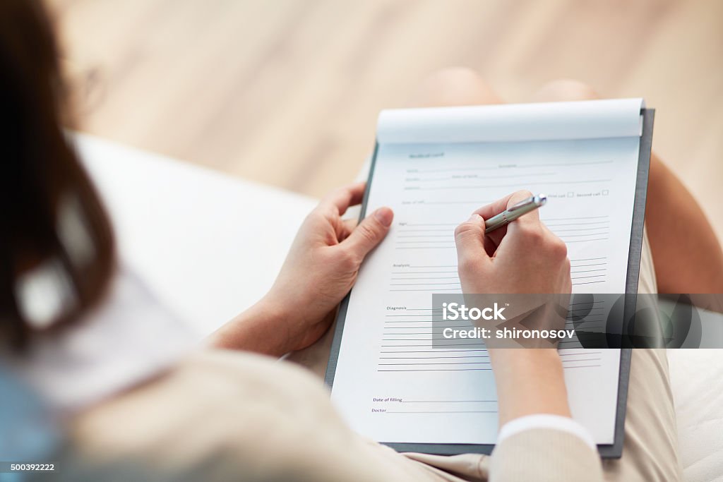 Medical record Female counselor writing down some information about her patient Questionnaire Stock Photo