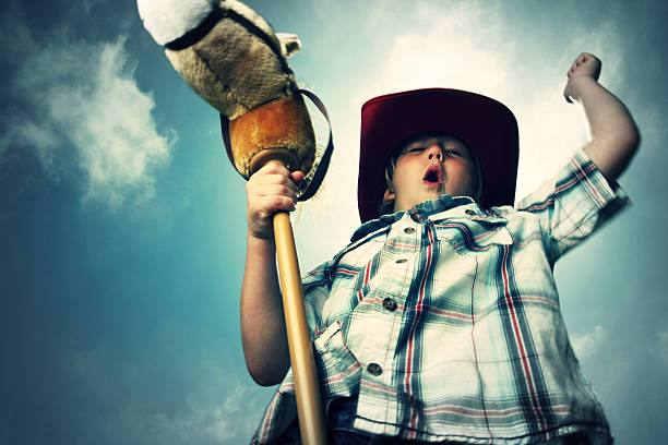 An adorable African American cowboy happily swinging a long rope.  On a white background.