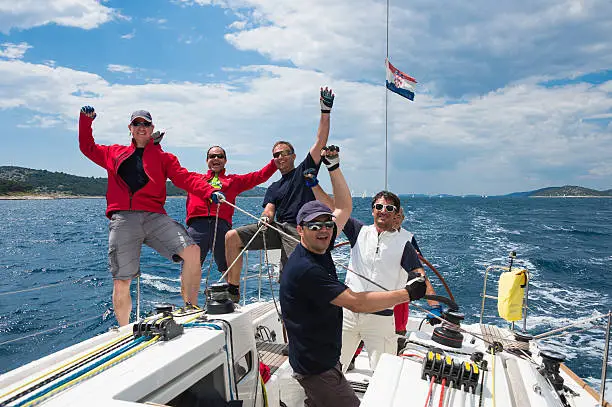 Front view of sailboat racing at regatta, six crew members celebrating the first place, Adriatic sea, Croatia,Europe