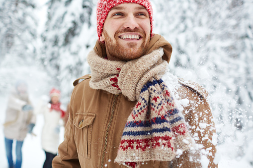 Happy guy in winterwear on background of his friends
