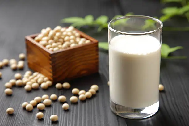 close up shot of a glass of soymilk and soybeans