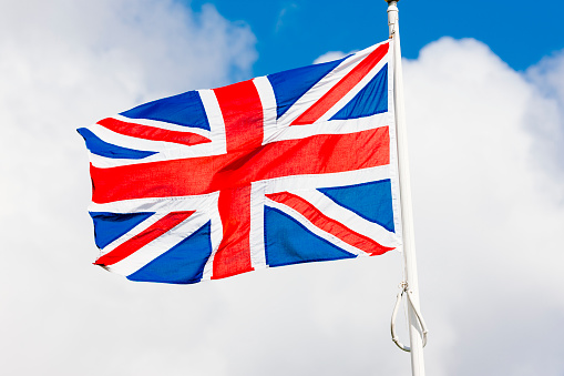 United Kingdom national flag on flagpole fluttering on the wind against the sky. AdobeRGB colorspace.