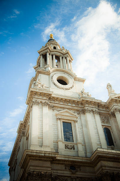 A beam of sunlight shines down on the southwestern tower of the front facade of St Paul's Cathedral in London.
