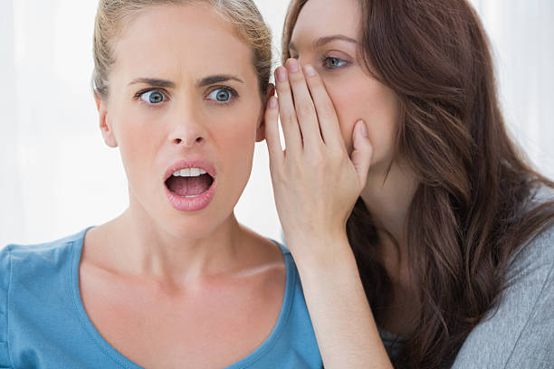 istock Brunette whispering secret to her friend 500402919