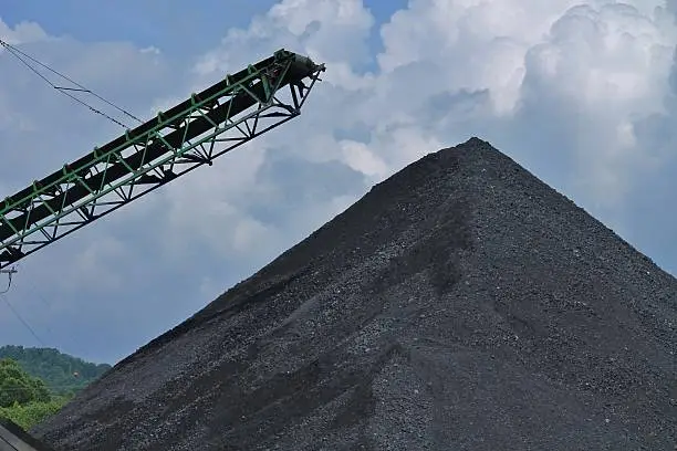 Large pile of pebble coal beside of a coal conveyor belt.