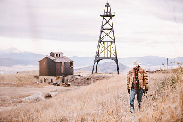 istock Rugged man walking through field with oil drill and barn 500408649