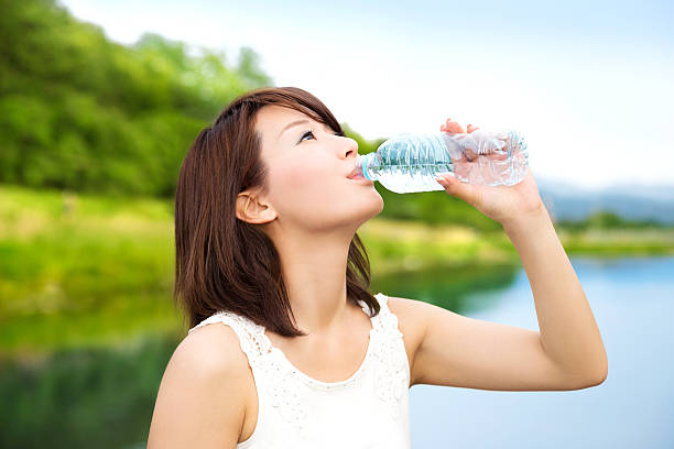 hermosa chica asiática bebiendo de la botella de agua en la naturaleza - lake asia young women beautiful people fotografías e imágenes de stock