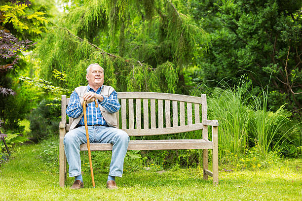 Senior man sitting on park bench stock photo