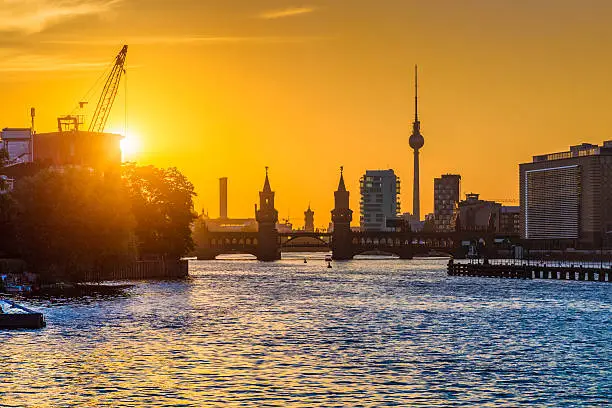 Beautiful view of Berlin skyline with famous TV tower and Oberbaum Bridge at river Spree in golden evening light at sunset, Berlin Friedrichshain-Kreuzberg, Germany.