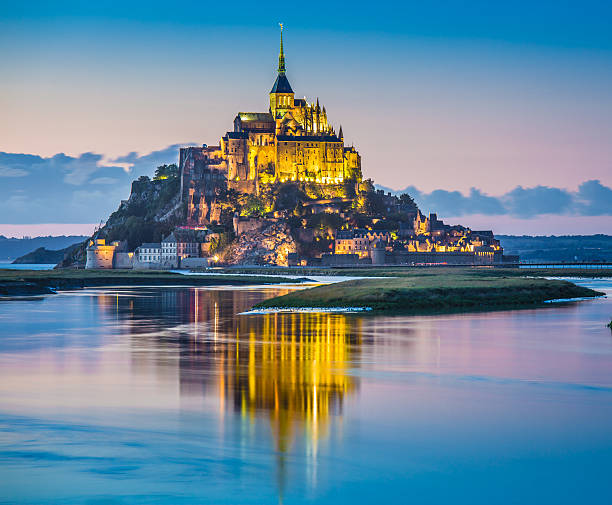 Mont Saint-Michel in twilight at dusk, Normandy, France Panoramic view of famous Le Mont Saint-Michel tidal island in beautiful twilight during blue hour at dusk, Normandy, northern France mont saint michel photos stock pictures, royalty-free photos & images