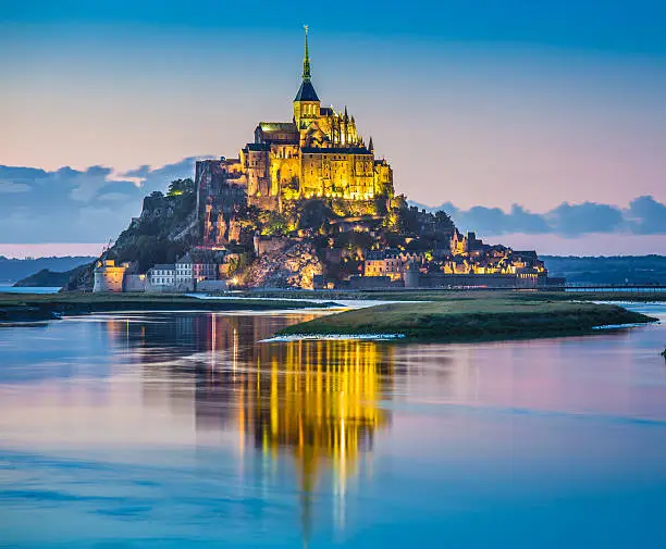 Panoramic view of famous Le Mont Saint-Michel tidal island in beautiful twilight during blue hour at dusk, Normandy, northern France