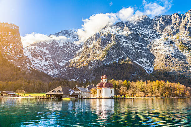 Lake Konigssee with St. Bartholomae pilgrimage church in fall, Bavaria Panoramic view of scenic mountain scenery with Lake Konigssee with world famous Sankt Bartholomae (St. Bartholomew) pilgrimage church in fall, Nationalpark Berchtesgadener Land, Bavaria, Germany. bavarian alps photos stock pictures, royalty-free photos & images